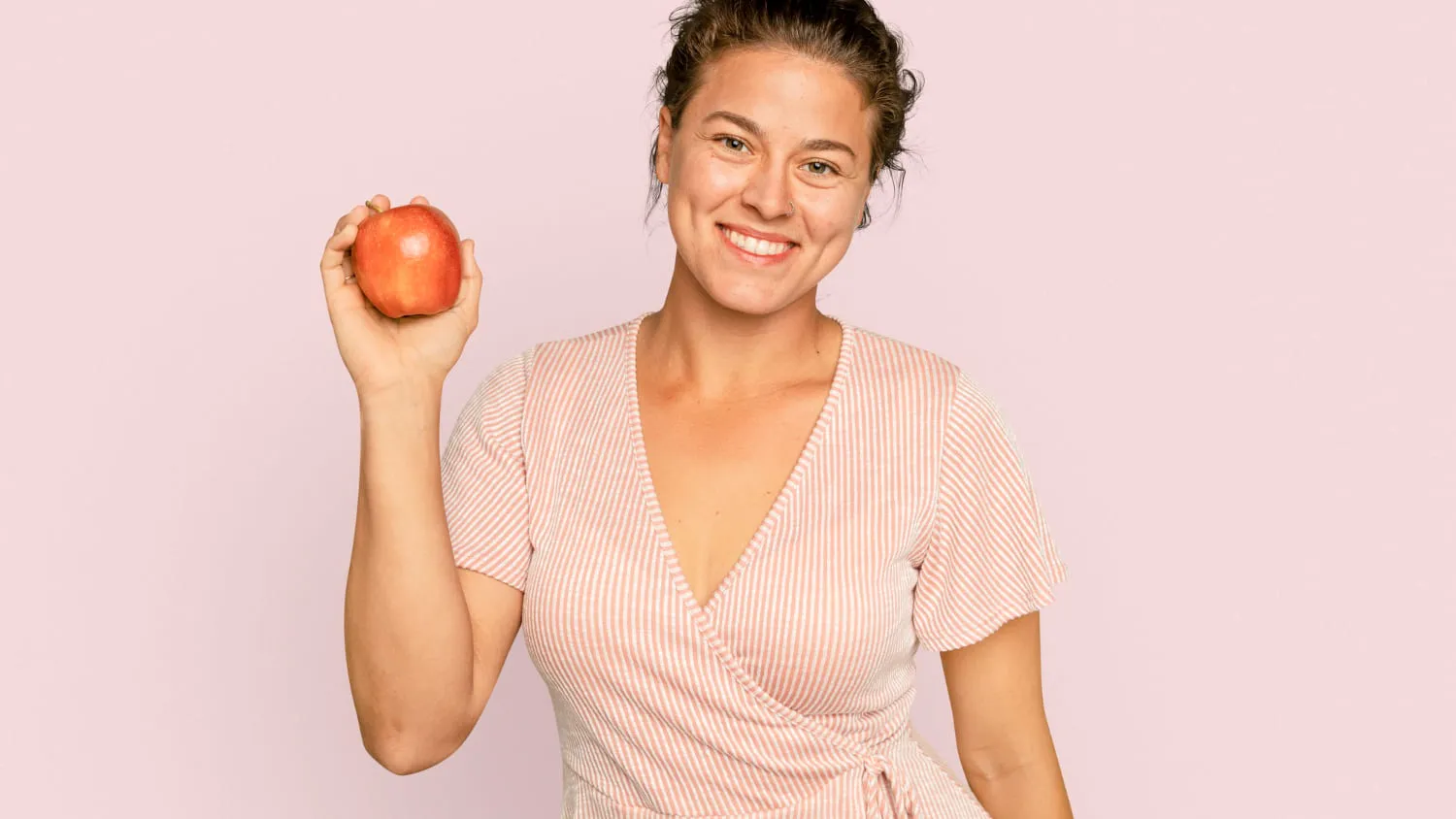 A woman smiling and holding an apple
