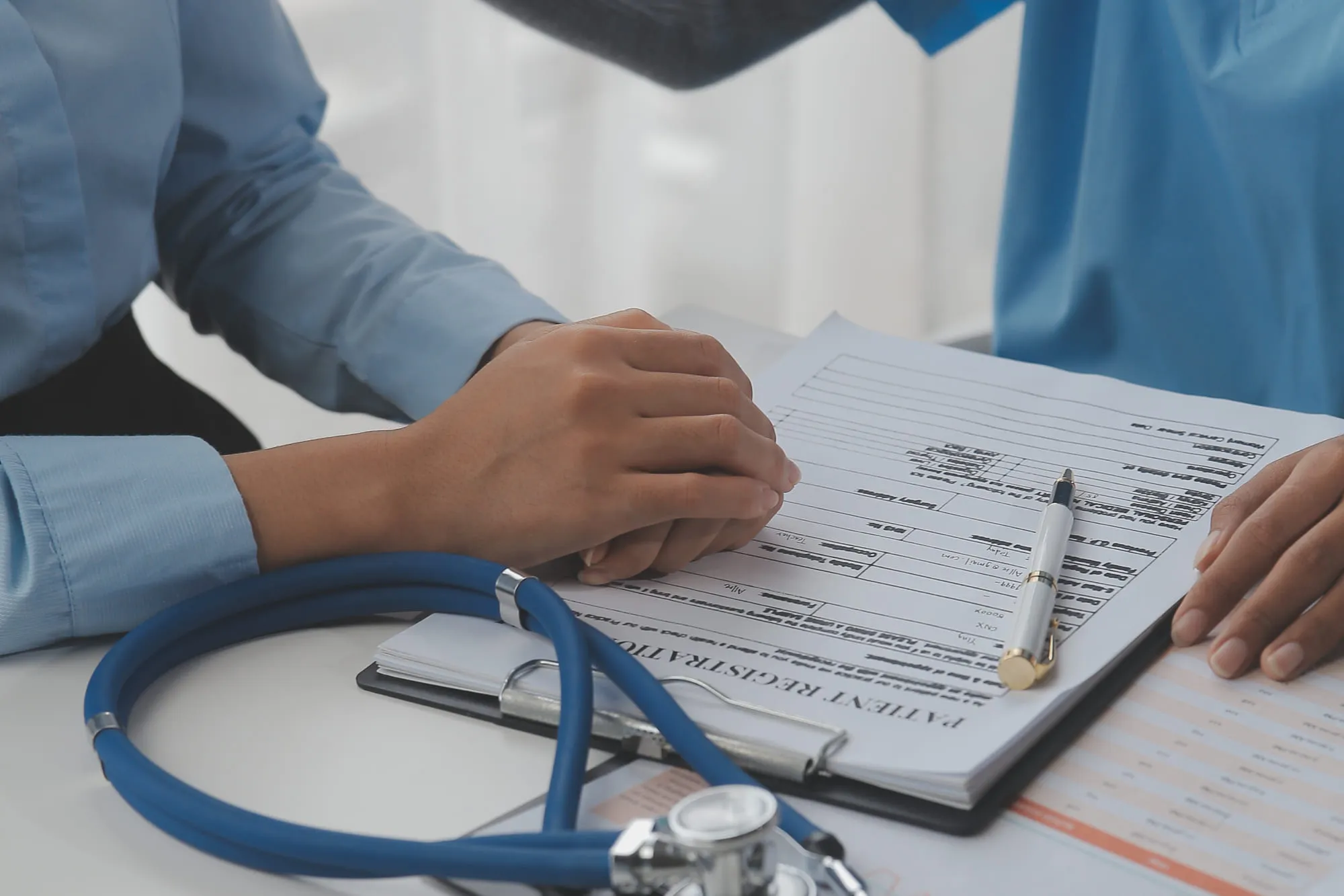 A clinician filling in a workplace medical form on a clipboard beside a stethoscope