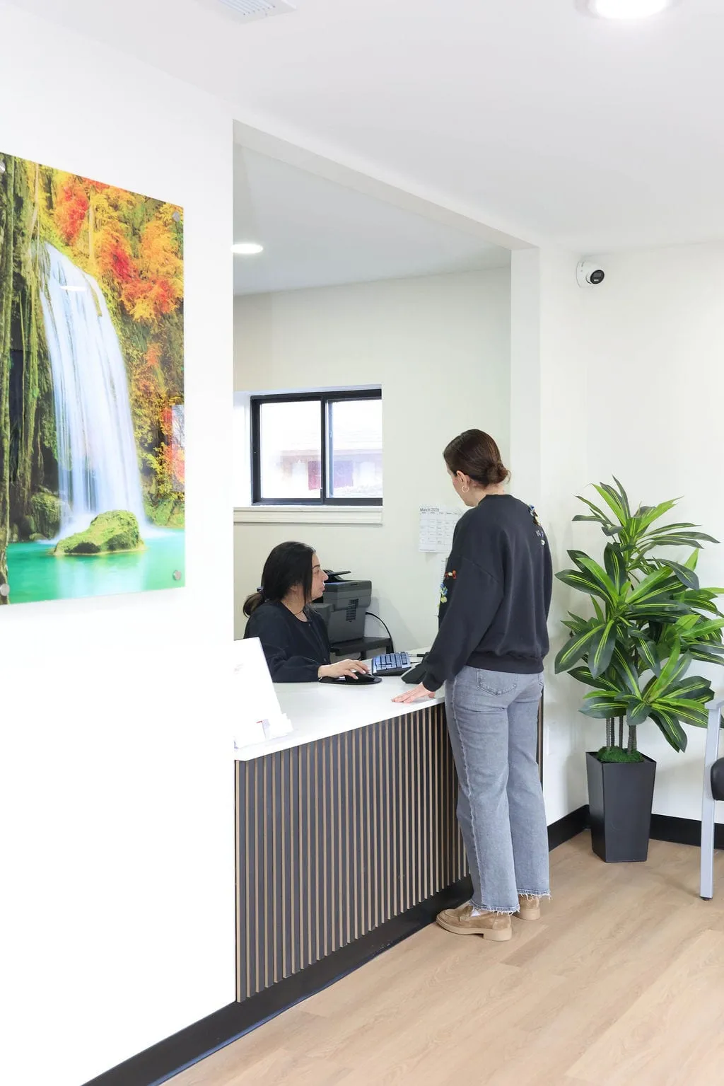 A patient checking in at the Serenity Urgent Care reception desk
