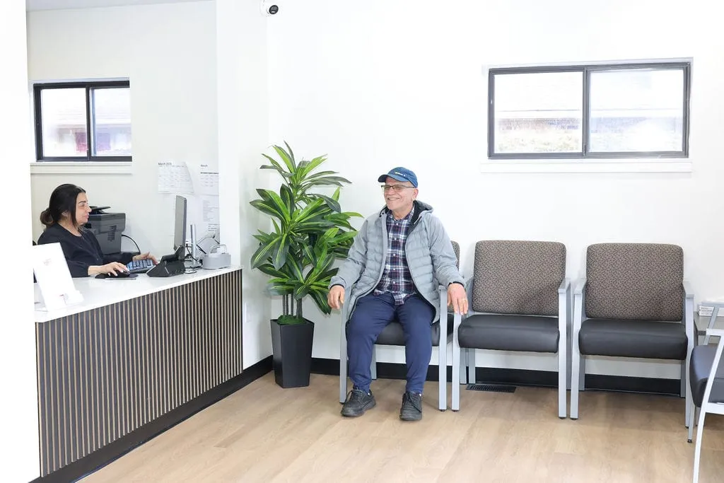 A patient waiting to be seen in the Serenity Urgent Care waiting area, with the front desk behind
