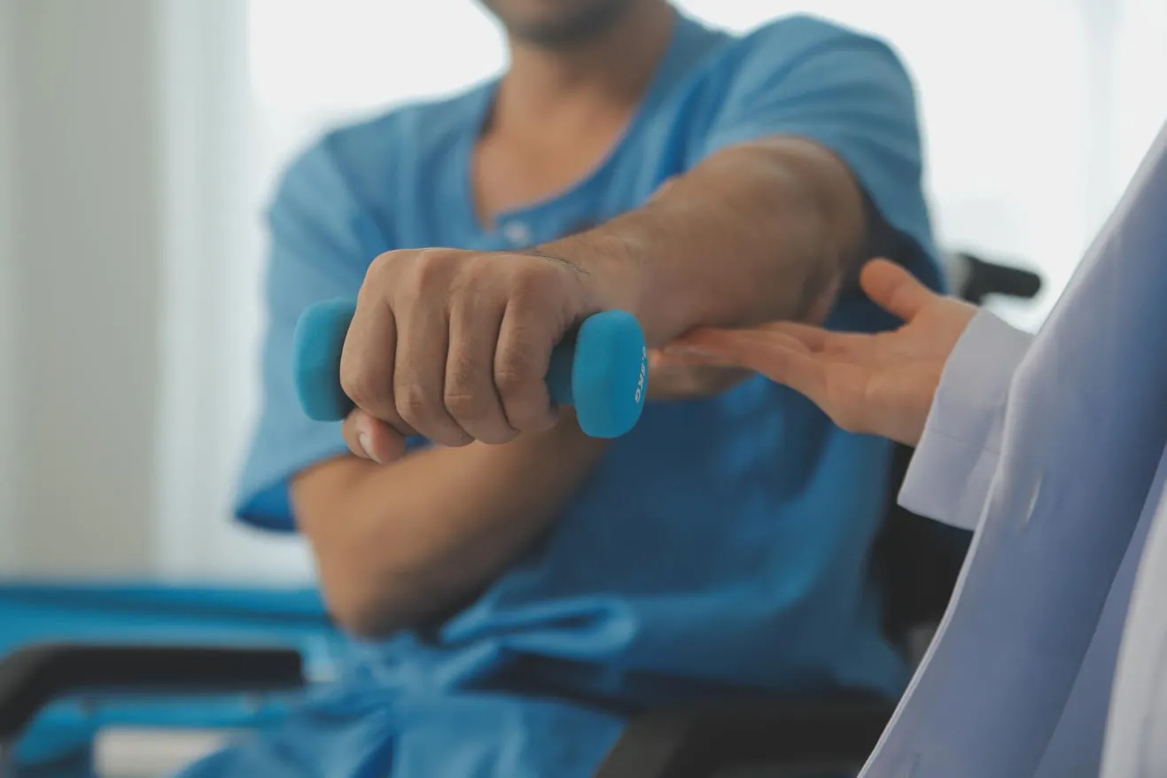 A clinician supporting a patient's arm during a strength check, the patient holding a small dumbbell