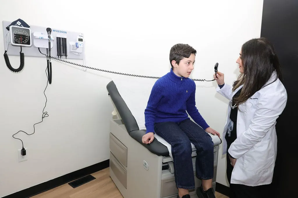 A provider examining a school-age patient on the exam table