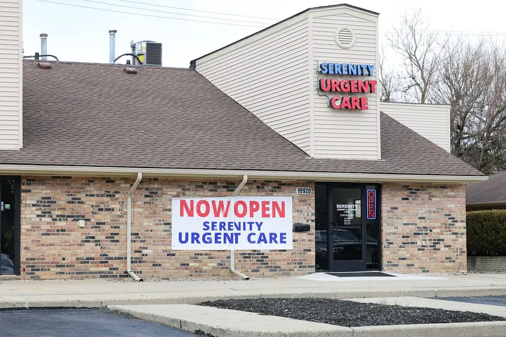 The Serenity Urgent Care building on Farmington Road in Livonia, with a Now Open banner beside the entrance