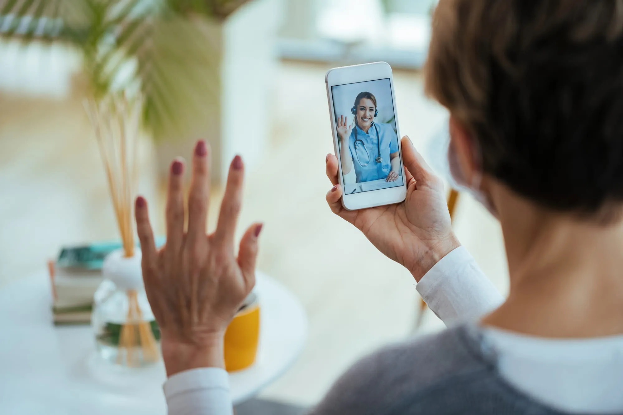 A patient at home speaking with a clinician during a video visit on their phone