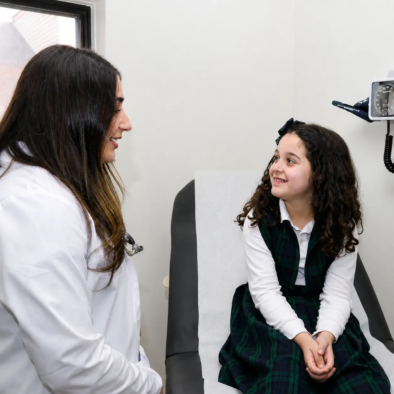 Primary care physician talking with a young patient during a routine medical visit at Serenity Urgent Care & Primary Care Clinic in Livonia, Michigan.